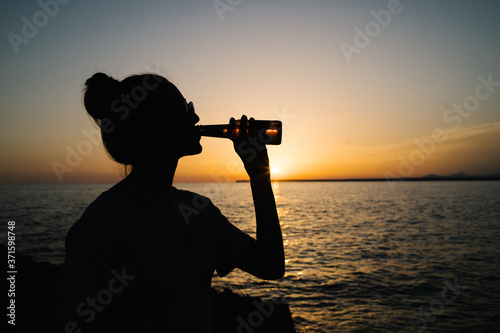 silhouette of a girl drinking beer on a sunset