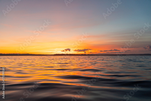 Water surface. View of a Sunset sky background. Dramatic gold sunset sky with evening sky clouds over the sea. View of a Crystal clear sea water texture. Landscape. Small waves. Water reflection
