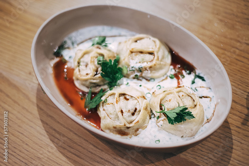 Manti - a delicacy dish of Central Asia, is a relative of dumplings and ravioli. Served with sauce on a plate in a cafe