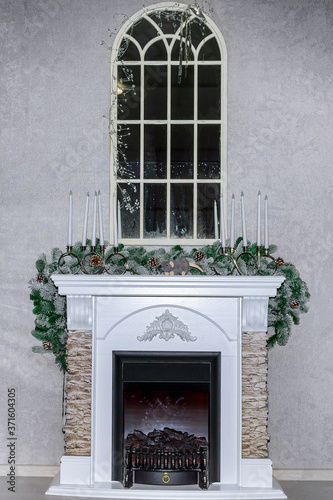 Fireplace decorated with spruce branches and candles. Christmas decorations. New Year's decorations.