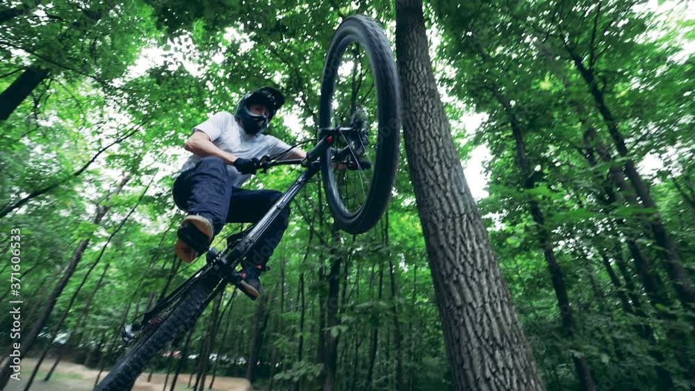 A man is doing stunt jumping on his bmx in the forest A man is doing stunt jumping on his bmx in the forest