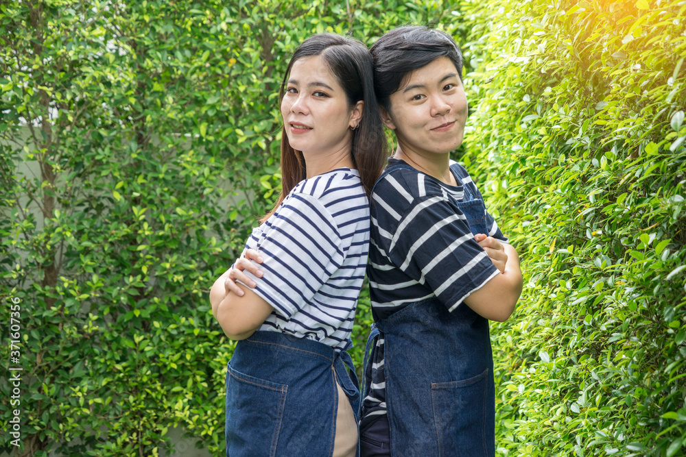 Woman with a tomboy, a lesbian couple standing with their arms folded in the backyard.LGBT concept