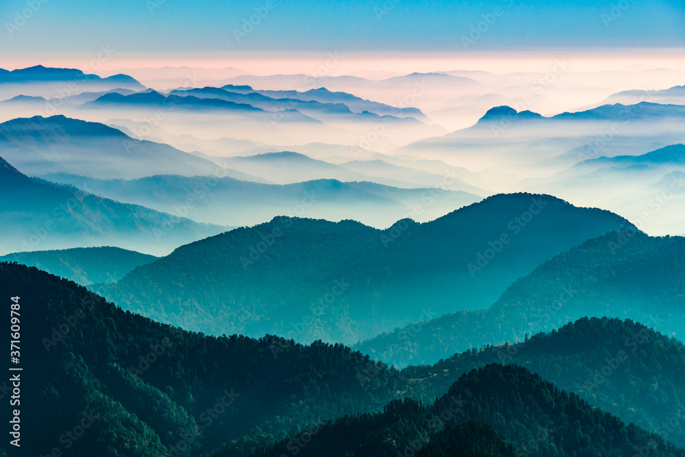 View of Himalayas mountain range with visible silhouettes through the colorful fog from Khalia top trek trail. Khalia top in himalayan region of Kumaon, Uttarakhand, India. - obrazy, fototapety, plakaty 