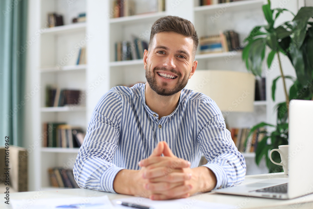 Young modern business man working using laptop while sitting in the office. Young modern business man working using laptop while sitting in the office.