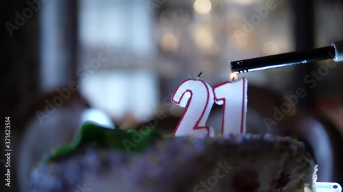 Lighting candles 21 Birthday cake. Numbers twenty one wick burning. Dolly move isolated close up. photo