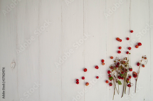 wild strawberries on a white wooden background, top view, place to copy