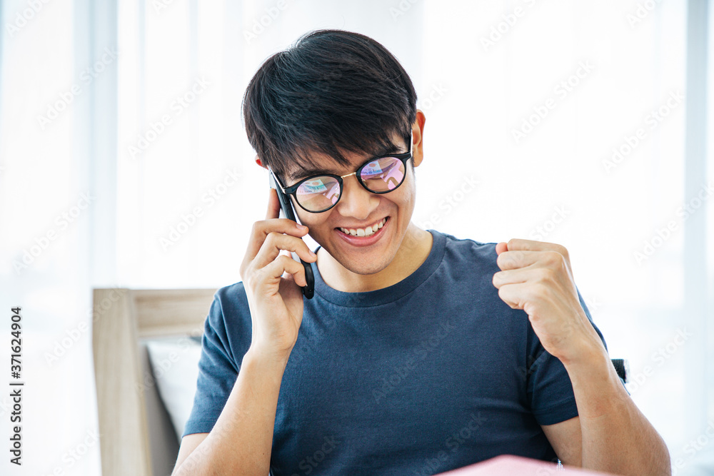 Surprised happy asian man using mobile phone on desk read good news on internet, amazed asian guy winner excited win scream with joy celebrate victory success at home. WORK FROM HOME Concept. 