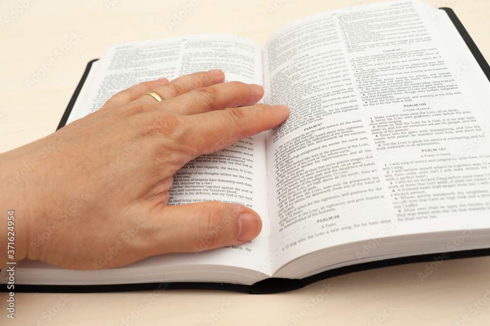 Fototapeta premium Hands on the Holy Bible in close-up. Studying and reading the Word of God. Top view