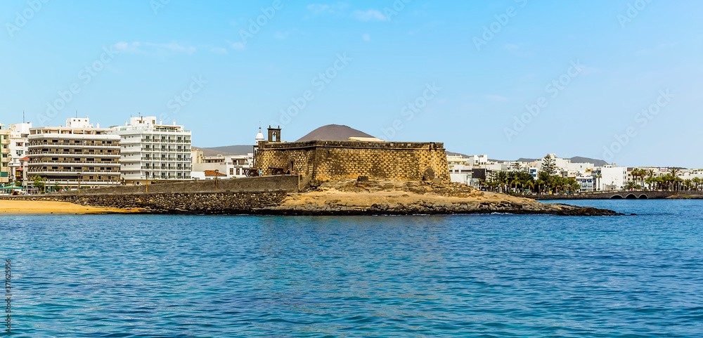 A view towards the Islet of the English and the Castle of Saint Gabriel from the harbour wall in Arrecife, Lanzarote on a sunny afternoon