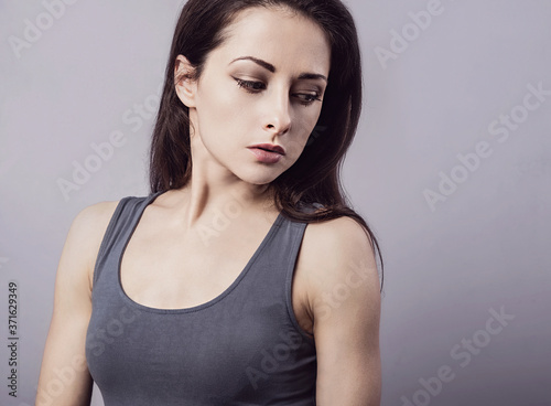 Unhappy depressed woman looking down in casual clothing. Tired female model. Concept. On grey backgriund with empty copy space.
