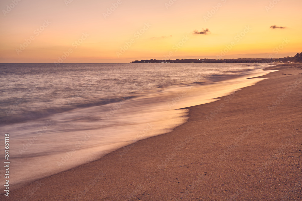 Sandy tropical beach at sunset, long exposure picture, summer vacations concept, color toning applied.
