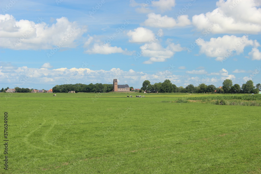 Nice view over the Dutch landscape with meadows and in the distance a typical old church with a church tower. Photo was taken on a sunny day in July. Nice view over the Dutch landscape with meadows and in the distance a typical old church with a church tower. Photo was taken on a sunny day in July.