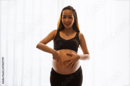 Close-up of a pregnant woman touching her belly on the foreground in emotional smile happy by asian woman Free Download Close-up of a pregnant woman touching her belly on the foreground in emotional smile happy by asian woman - GFXLoad