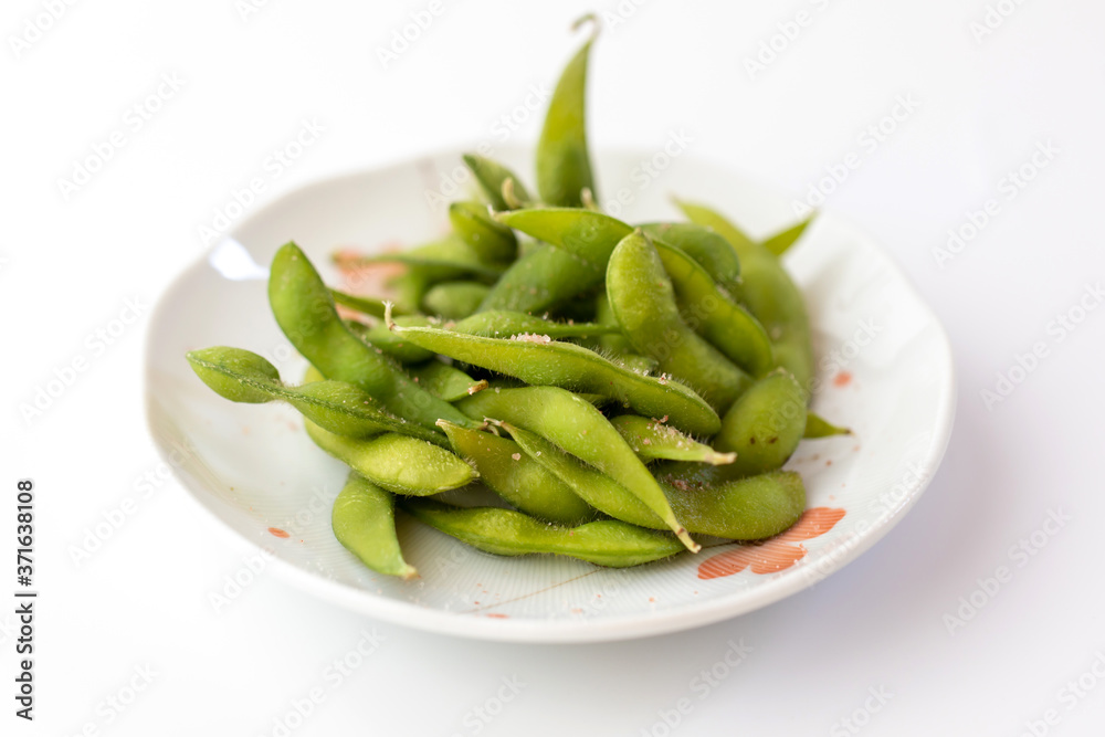 Edamame Nibbles, boiled green soy beans on a plate isolated on white, Japanese food. Edamame Nibbles, boiled green soy beans on a plate isolated on white, Japanese food.