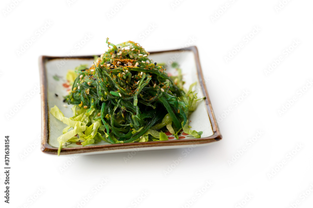 A delicious fresh Wakame also known as seaweed salad with chili pepper and sesame flakes, isolated on white background. A delicious fresh Wakame also known as seaweed salad with chili pepper and sesame flakes, isolated on white background.