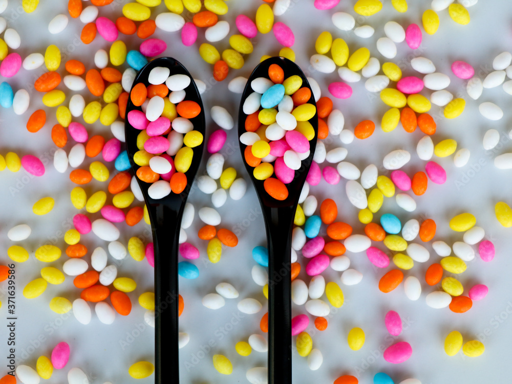 Multi colored fennel sugar candy in spoons and scattered as background