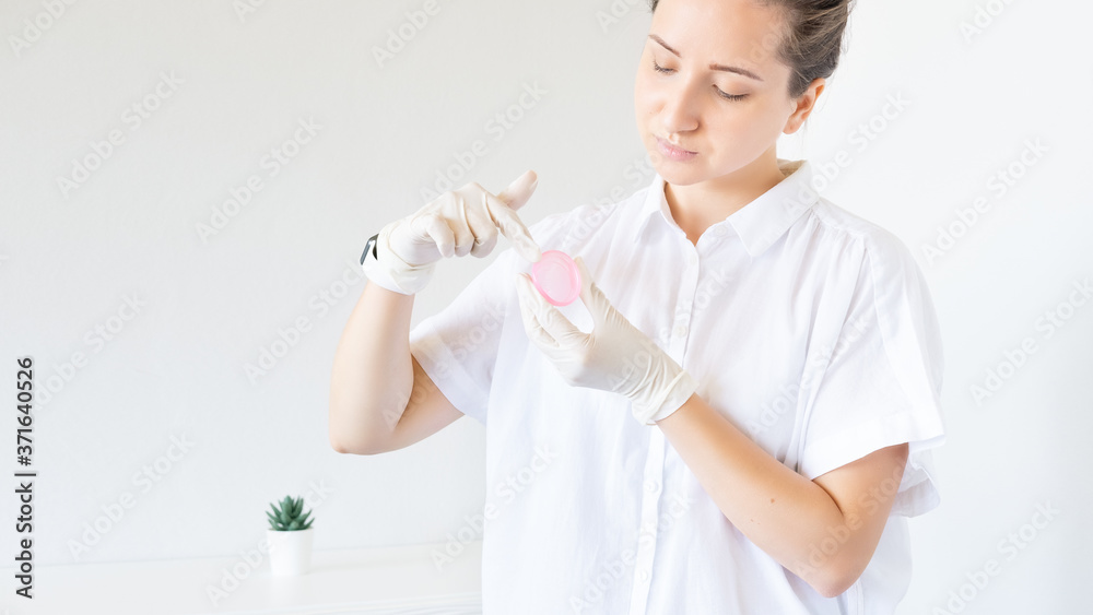 Female Gynecologist doctor showing pink period cup on white backdrop. Mentrual cup, zero waste, eco friendly. Replacement of absorbents Female Gynecologist doctor showing pink period cup on white backdrop. Mentrual cup, zero waste, eco friendly. Replacement of absorbents