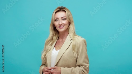 Wondered cheerful woman with sarcasm and derision pointing finger at camera and smiling, making fun of people, egoism. Indoor studio shot isolated on blue background