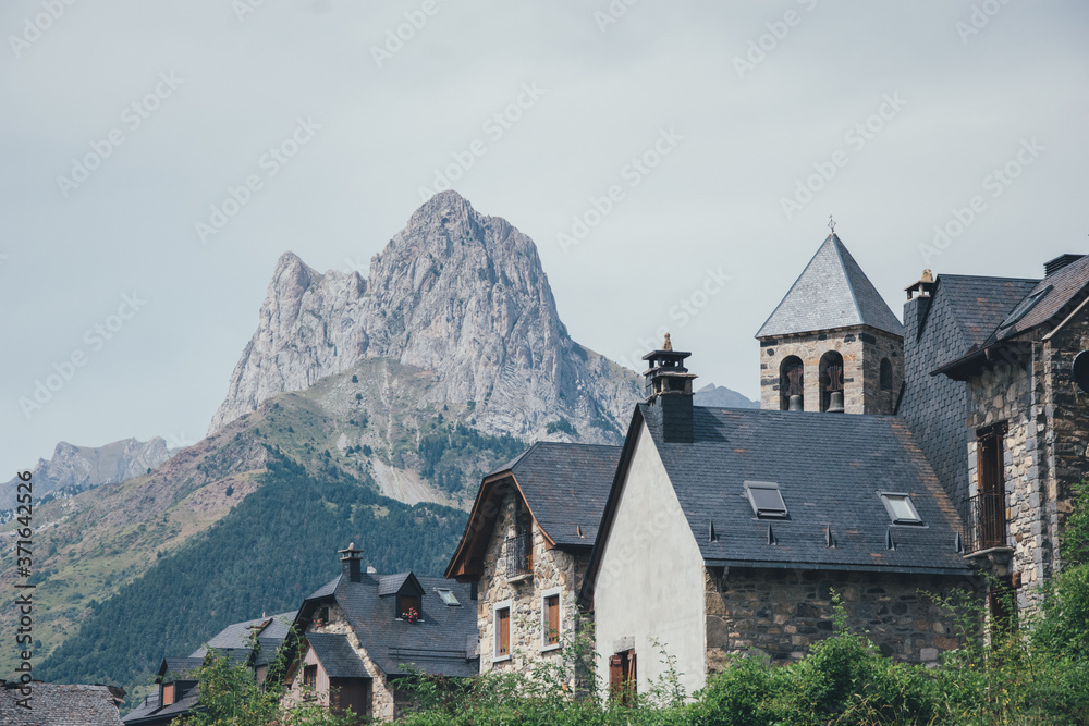 Tejados de pueblo medieval con montaña de fondo e iglesia. Vista del Peña Foratata, Lanuza