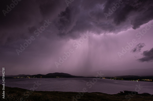 Stormy dramatic sky with heavy rain over lake