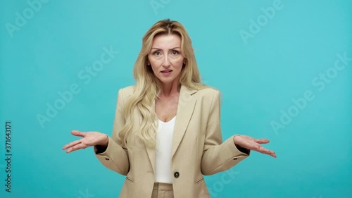 What? Serious strict middle aged woman in business suit shocked and irritated with news, dissatisfied with badly completed task, frustration. Indoor studio shot isolated on blue background