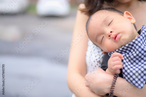 Little boy sleepinh in his mother's arms. Woman carrying her newborn son. photo