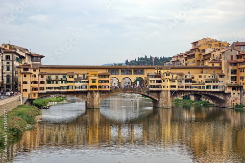 The Arno river with the famous Ponte Vecchio (Old Bridge), a medieval stone arch bridge with shops built along it, in Florence, Italy