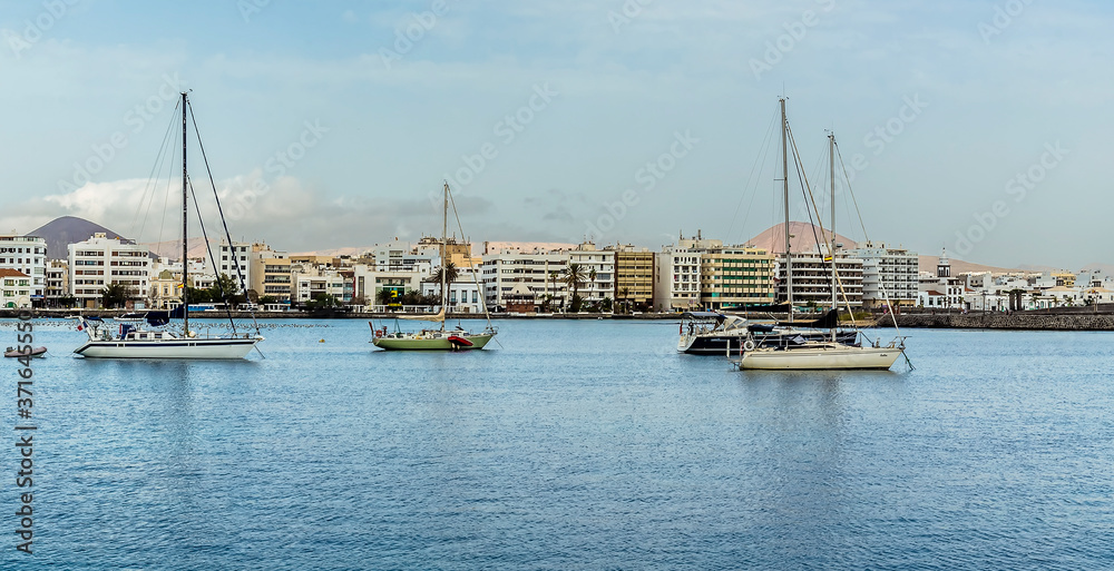 Yachts moored in a sheltered bay with the backdrop of the shoreline of Arrecife, Lanzarote on a sunny afternoon