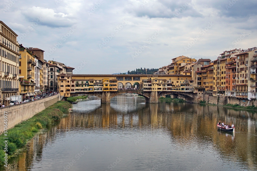 The Arno river with the famous Ponte Vecchio (Old Bridge), a medieval stone arch bridge with shops built along it, in Florence, Italy