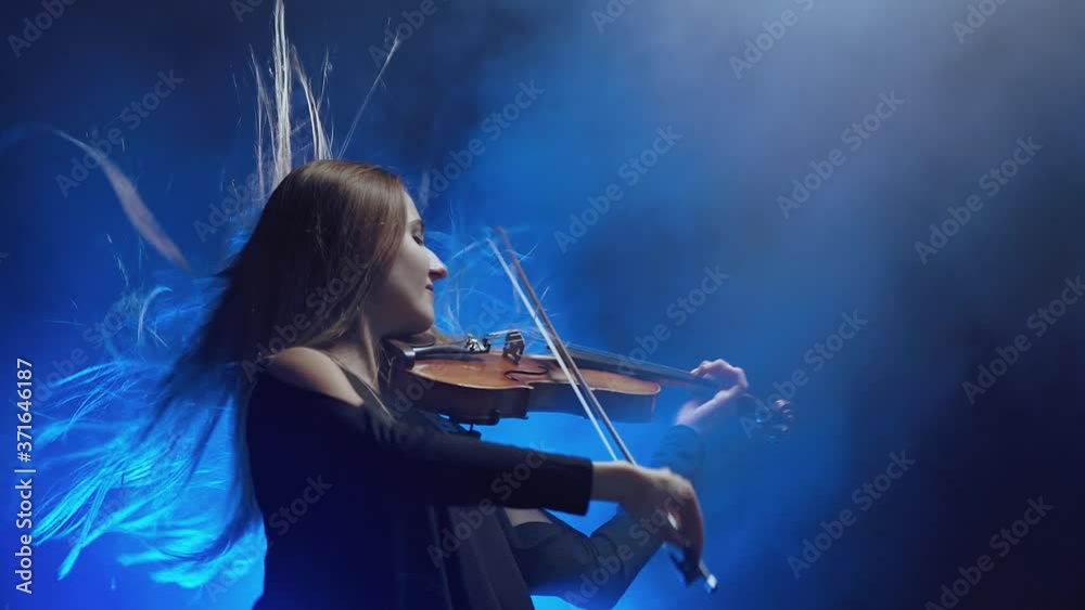 Girl violin musician playing at studio. Studio dark background