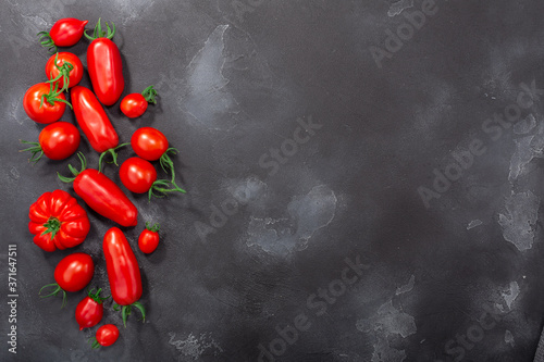 Red heirloom tomatoes on dark textured backdrop, top view
