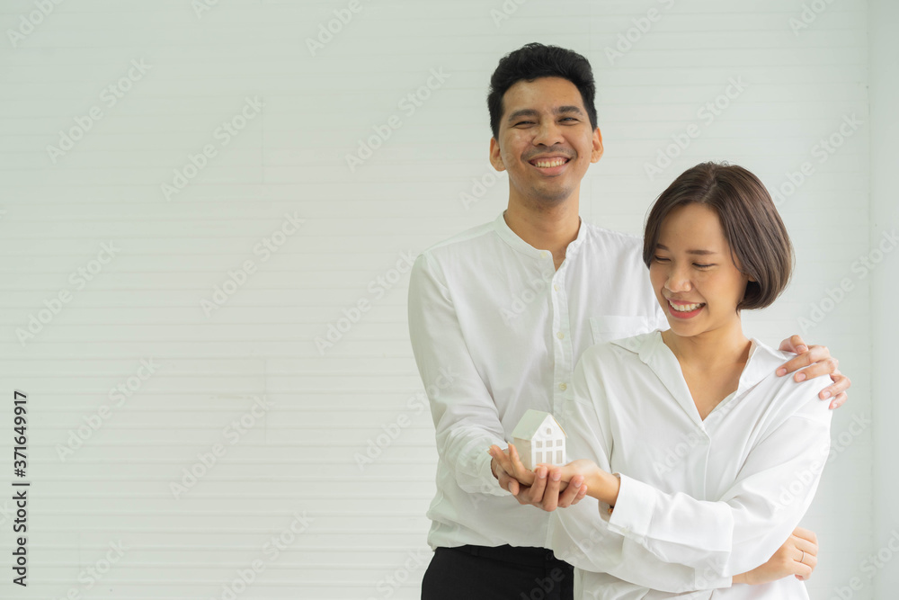 close up newly married couple standing inside home and holding house's model together for home loan and property investment concept close up newly married couple standing inside home and holding house's model together for home loan and property investment concept