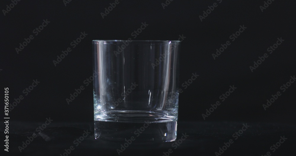 An empty whiskey, alcohol glass against a black background and floating smoke An empty whiskey, alcohol glass against a black background and floating smoke