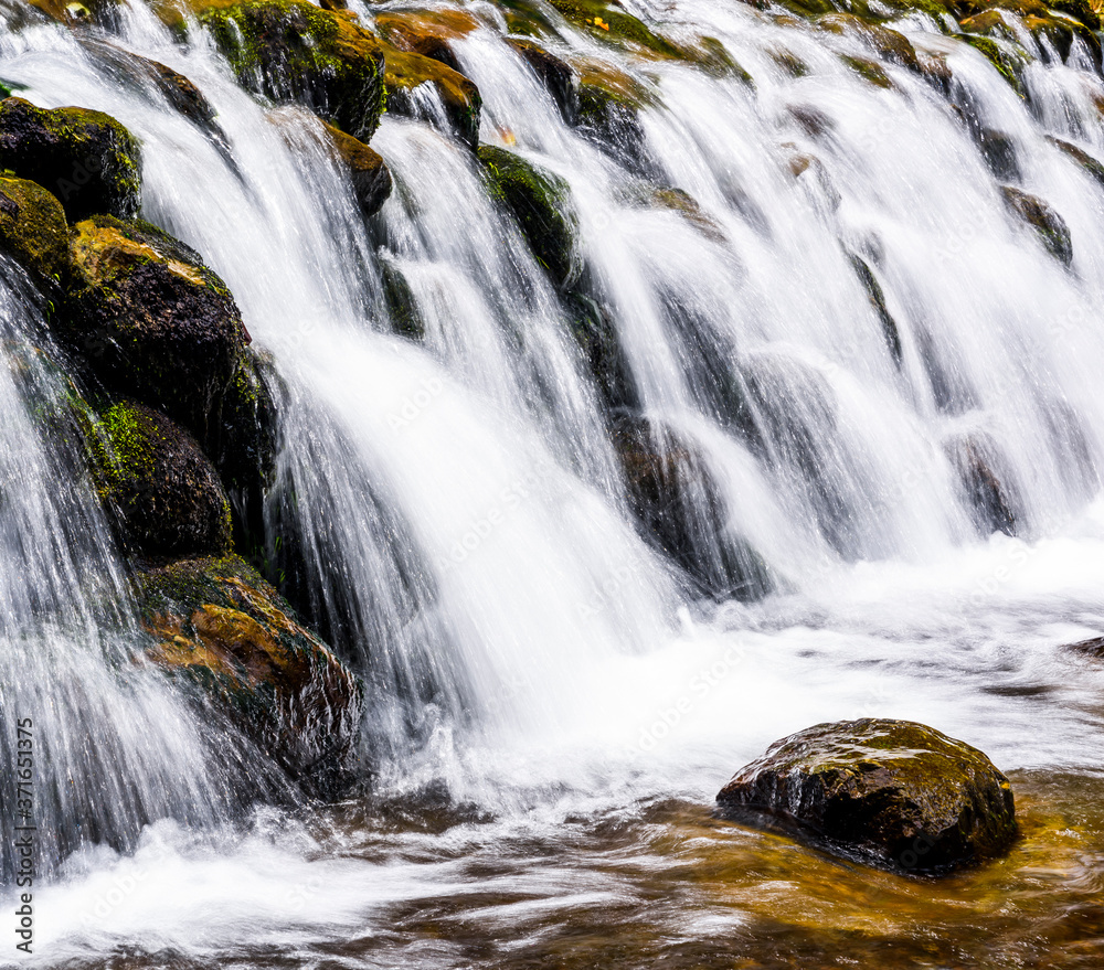 The stone under the waterfall, close-up waterfall as background.