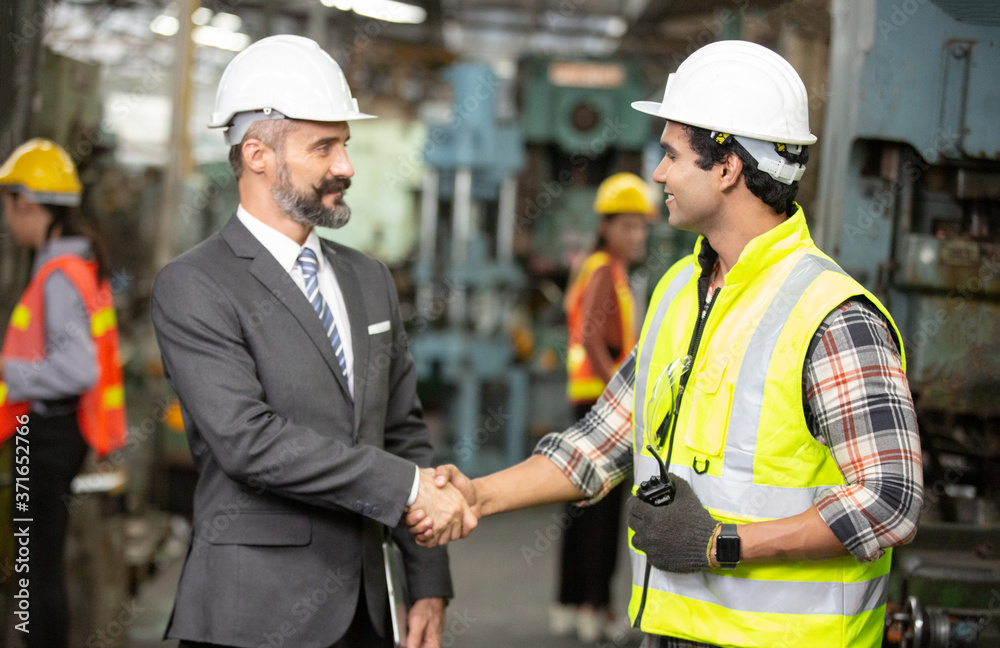 Business director and Mechanic engineer hand shaking at factory shop floor. Business director and Mechanic engineer hand shaking at factory shop floor.