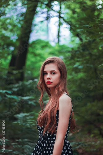 Portrait of a bright girl with long hair in nature. Expressive eyes and red lips