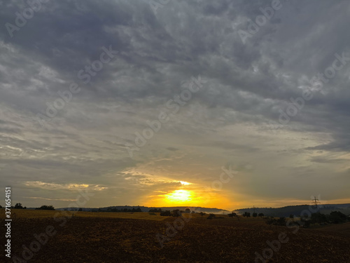 Sonnenuntergang am Horizont mit dunklen Wolken am weiten Himmel