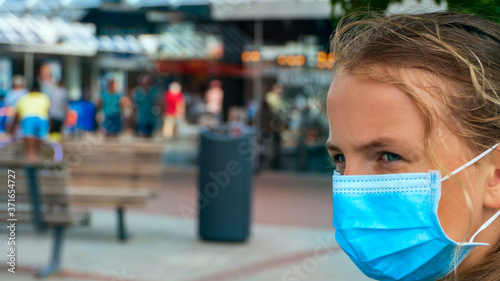 A young girl wears a face mask on the streets of the city.Cute Teenage Girl with a surgical mask on her face that protects against the spread of coronavirus disease.