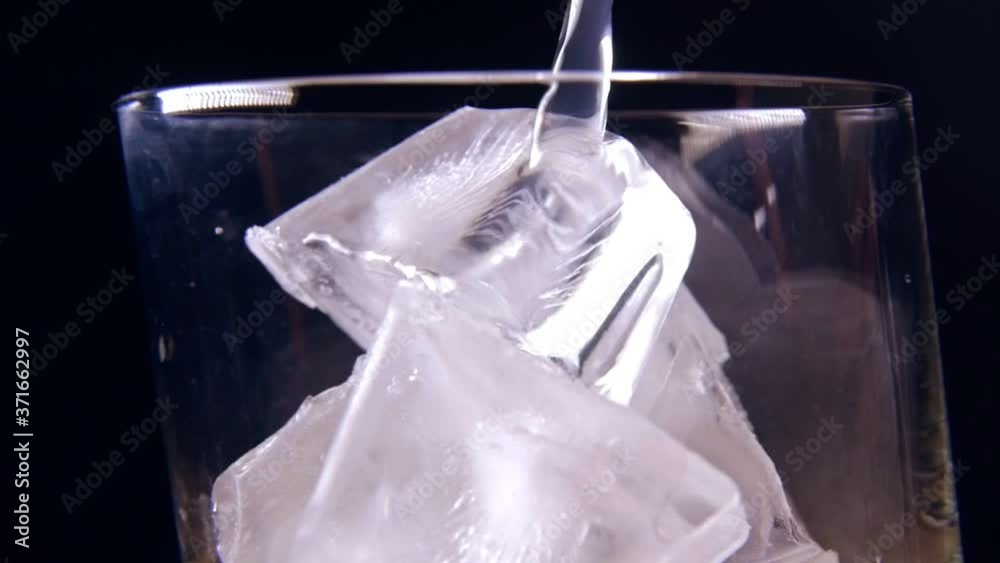 Pouring tonic water into glass with ice closeup slow motion sparkling water Pouring tonic water into glass with ice closeup slow motion sparkling water