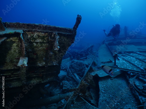 scuba divers exploring shipwreck scenery underwater ship wreck deep blue water ocean scenery of metal underwater and fish around © underocean