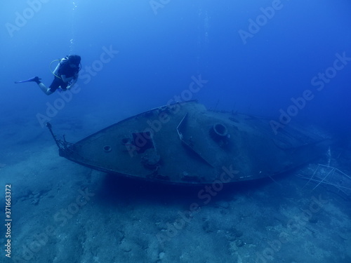 scuba divers exploring shipwreck scenery underwater ship wreck deep blue water ocean scenery of metal underwater and fish around