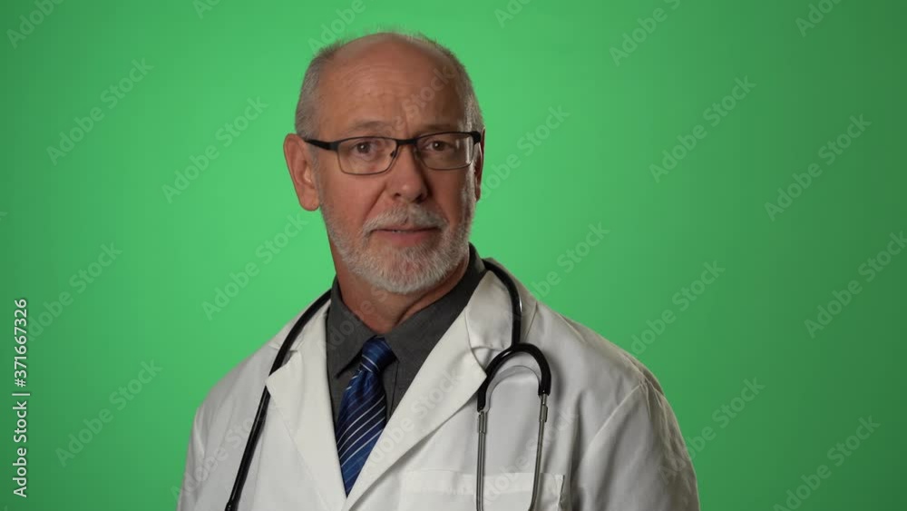 Male doctor wearing a lab coat and stethoscope portrait giving medical advice and consulting with a patient via a video conferencing call on green screen. Male doctor wearing a lab coat and stethoscope portrait giving medical advice and consulting with a patient via a video conferencing call on green screen.