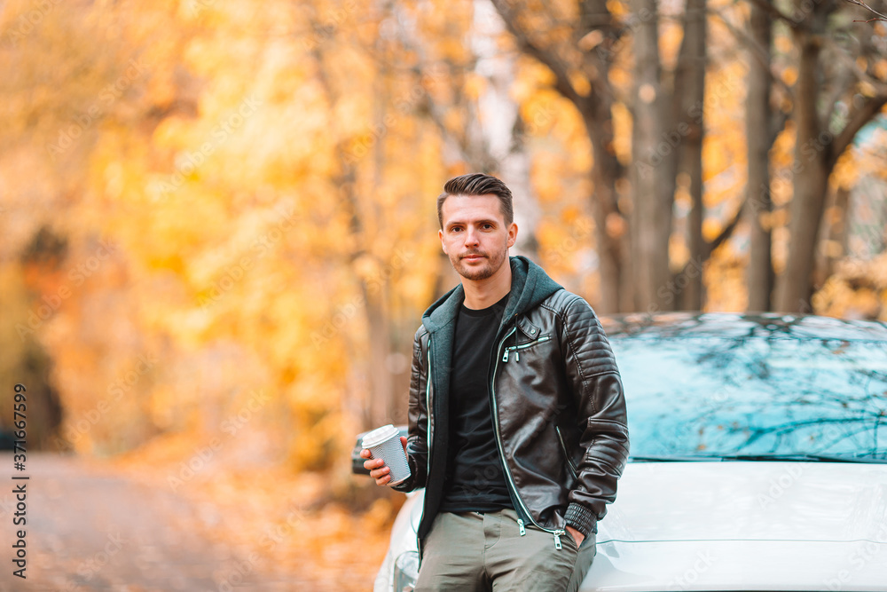 Young man drinking coffee with phone in autumn park outdoors Young man drinking coffee with phone in autumn park outdoors