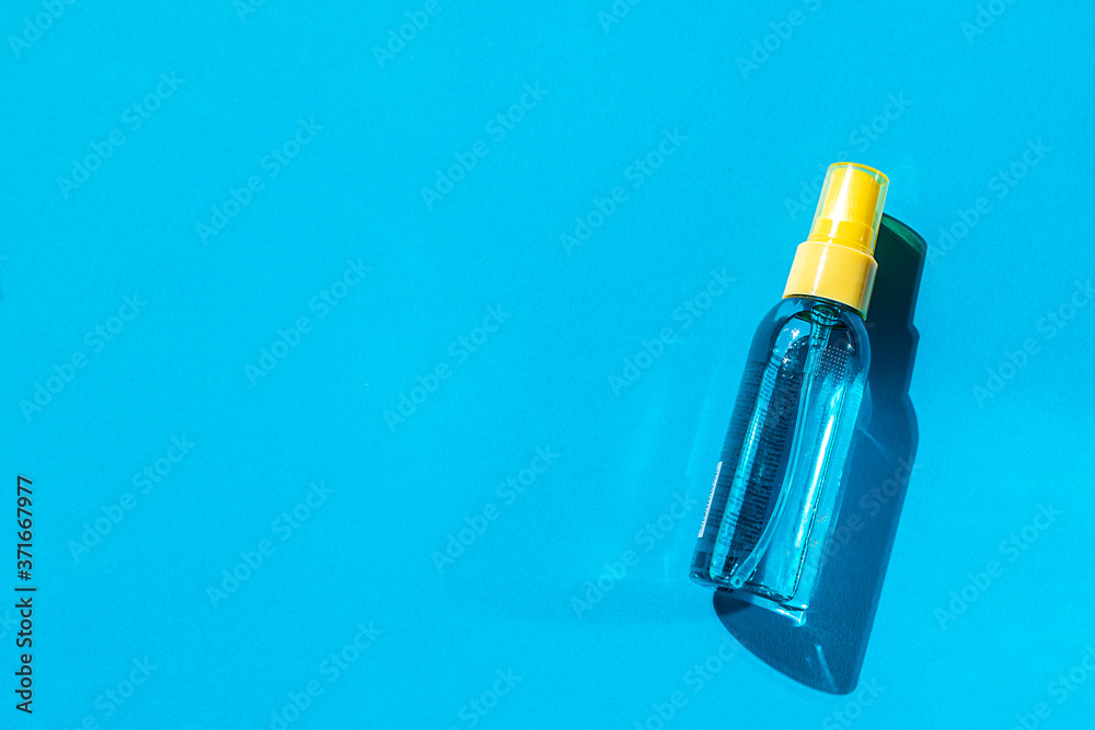 Cosmetic spray bottle blue and yellow with transparent liquid on a blue background. Spa cosmetics. Natural skincare. Cosmetic spray bottle blue and yellow with transparent liquid on a blue background. Spa cosmetics. Natural skincare.