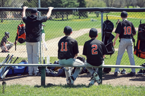 Teenagers in dugout behind chainlink fencing, shallow focus
