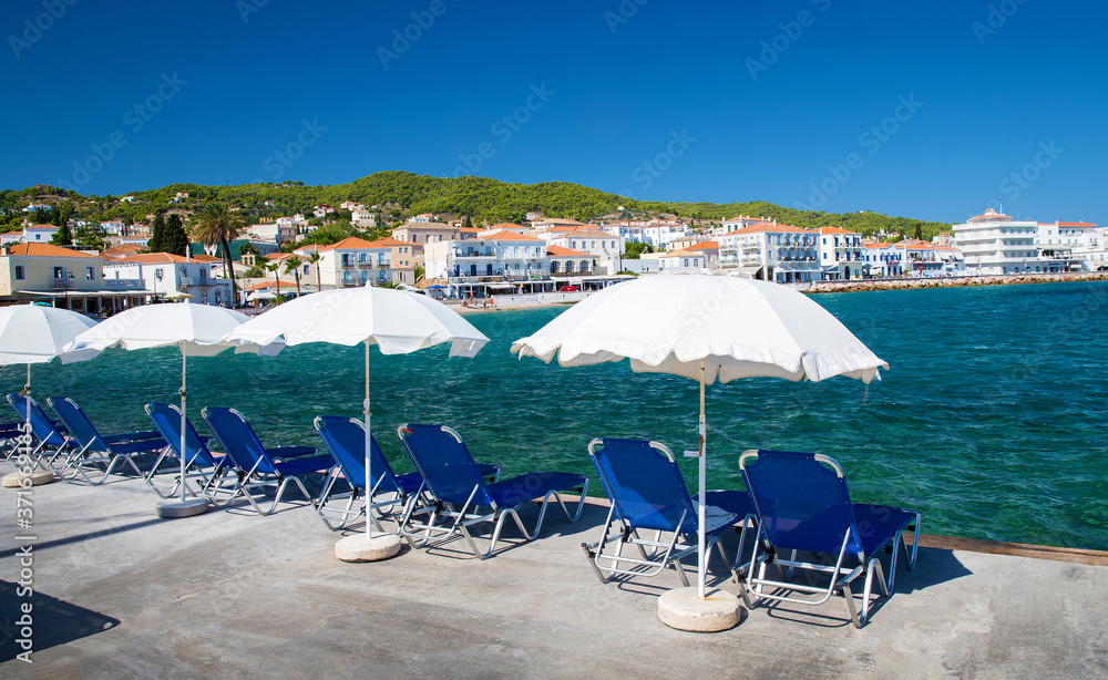 Umbrellas and beach chairs on beach in idyllic Greek island Spetses Umbrellas and beach chairs on beach in idyllic Greek island Spetses