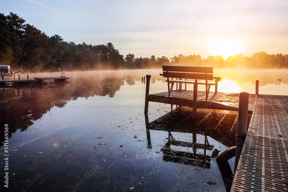 Naklejka premium Fog over lake at sunrise from a dock during autumn