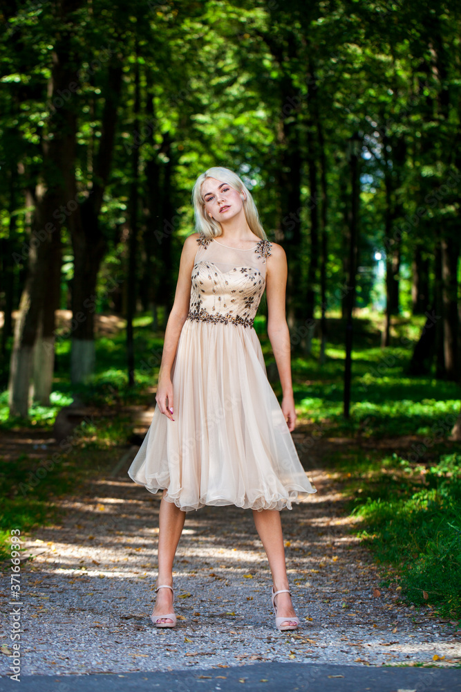 Young beautiful blonde girl in beige dress, summer park outdoor