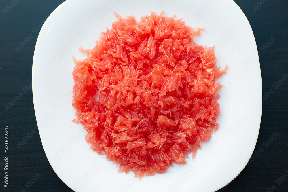 Red grapefruit fiber close-up. Fresh juicy cutted grapefruit without seeds and section shell on white plate. Red grapefruit fiber close-up. Fresh juicy cutted grapefruit without seeds and section shell on white plate.