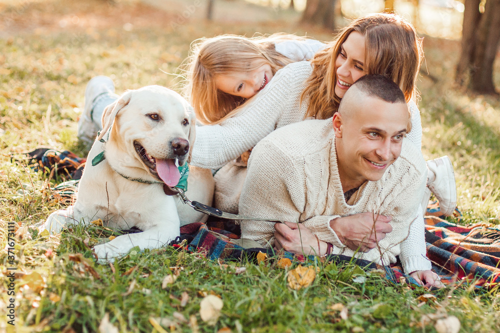Happy family is having fun with dog labrador are lying on green grass in park. Happy family is having fun with dog labrador are lying on green grass in park.
